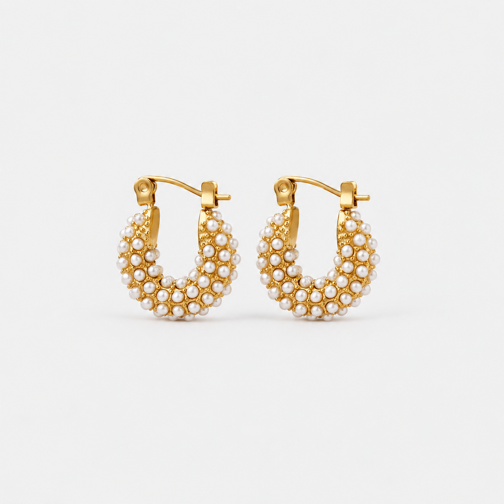 A pair of gold hoop earrings adorned with rows of small white pearls, displayed against a clean, light gray background.