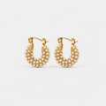 A pair of gold hoop earrings adorned with rows of small white pearls, displayed against a clean, light gray background.