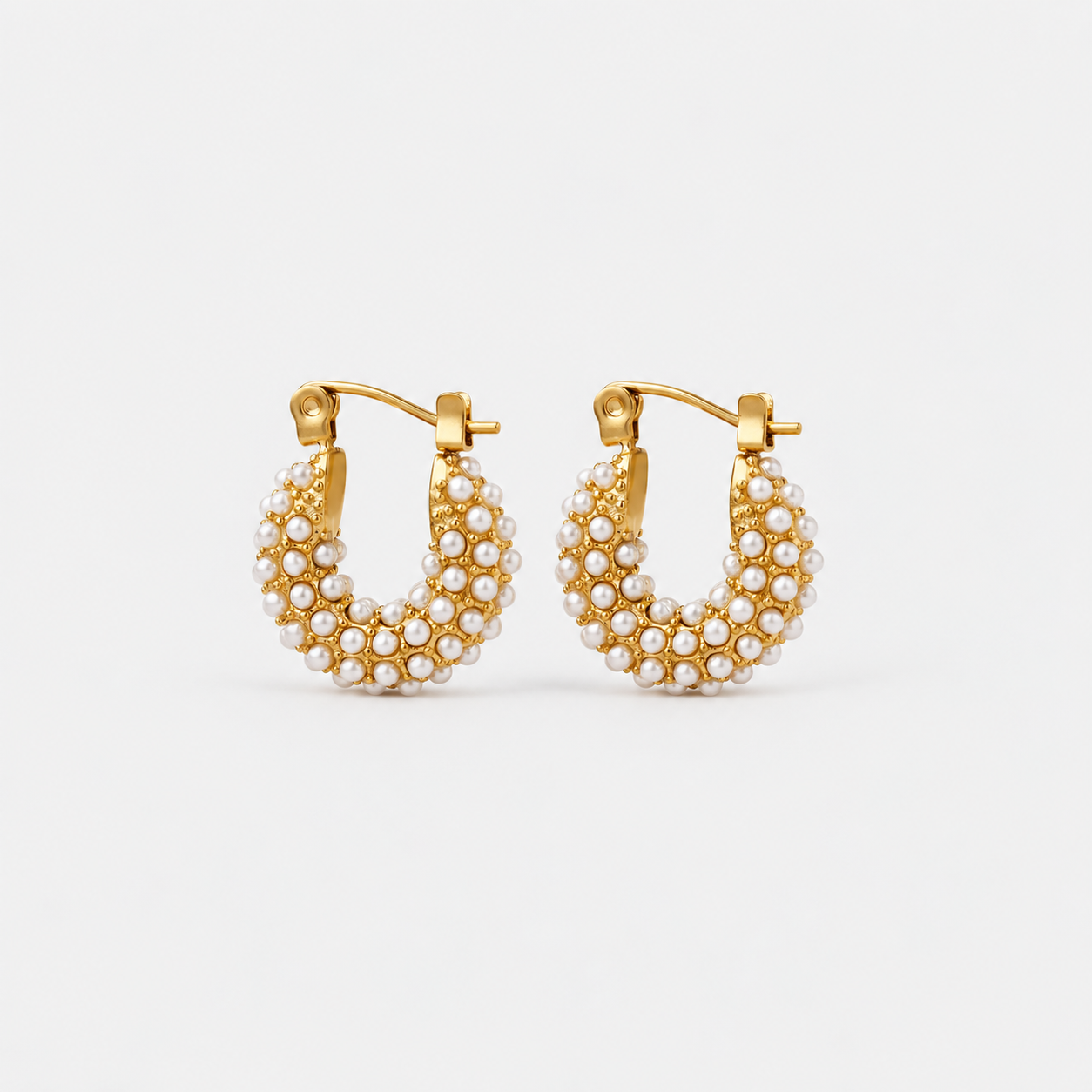 A pair of gold hoop earrings adorned with rows of small white pearls, displayed against a clean, light gray background.